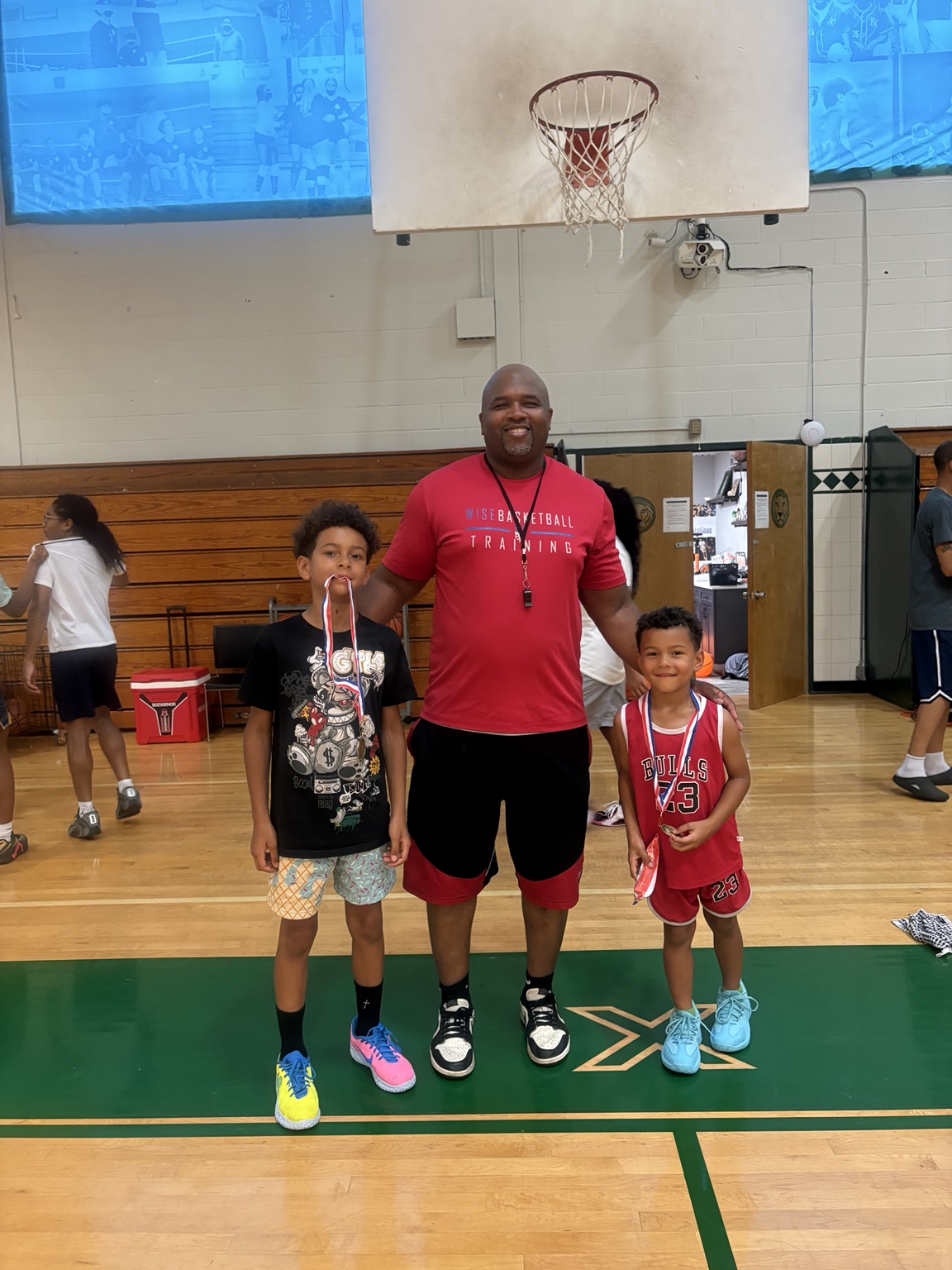 Coach Jamar Wise with two kids wearing medals