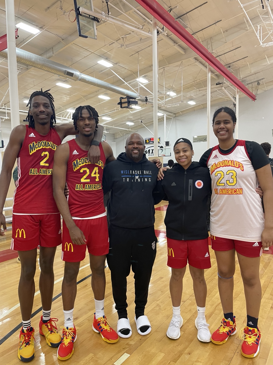 Coach Jamar Wise with players in red and white basketball uniforms