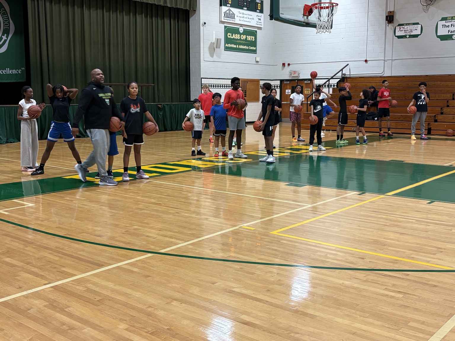 Large group of young players holding basketballs with coach Jamar Wise